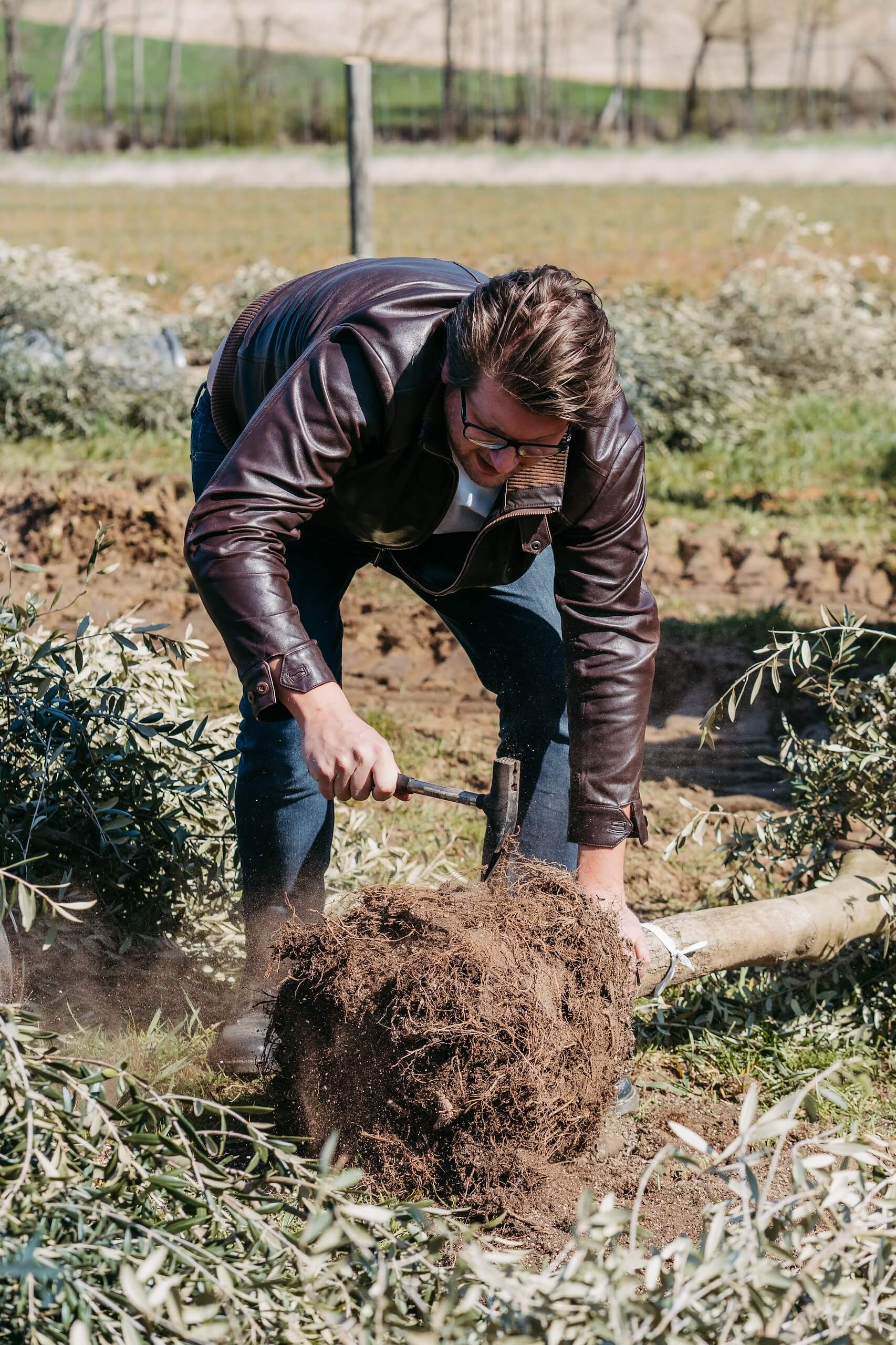 Mann pflanzt Baum für natürliche Hochzeitslocation im Freien, unterstreicht romantischen Hochzeitstraum im Grünen.