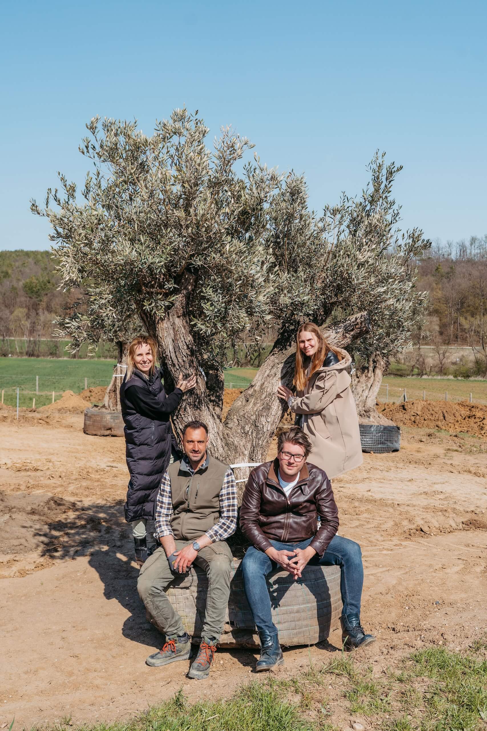 Menschen posieren vor einem alten Baum in idyllischer Landschaft—perfekte Kulisse für eine Traumhochzeit im Freien.